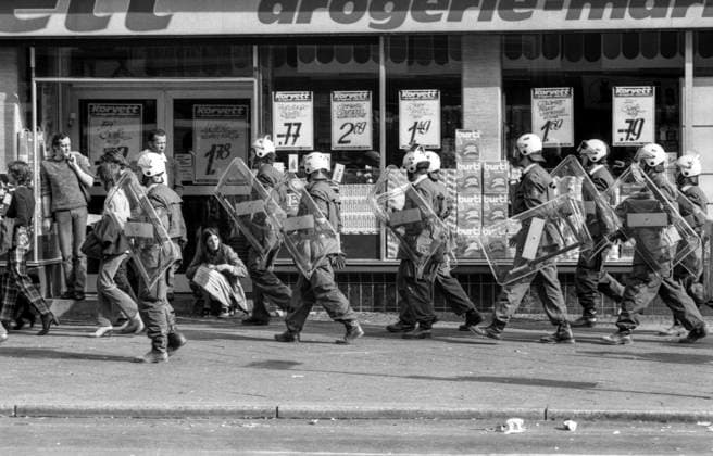 Potsdamer Str., Bülowstr., 22.9.1981 Der rechte Innensenator Heinrich Lummer (CDU) ließ am 22.9.1981 acht besetzte Häuser in der Bülowstr. 89, Winterfeldtstr. 20 22 24 (Schöneberg), Knobelsdorffstr. 40 42 (Charlottenburg), Dieffenbachstr. 27 (Kreuzberg) und Hermsdorfer Str. 4 (Reinickendorf) räumen und gab eine Pressekonferenz im geräumten Haus Bülowstr. 89, wo er sich provokativ auf dem Balkon zeigte. Die Polizei begann mit Schlagstöcken die Protestierenden in den fließenden Verkehr der Potsdamer Str. zu treiben. Dabei geriet der 18-jährige Klaus-Jürgen Rattay unter der Bülowbrücke unter einen BVG-Bus und wurde 80 m mitgeschleift. Er starb noch bevor der Krankentransport kam. *** Potsdamer Str , Bülowstr , 22 9 1981 The ri