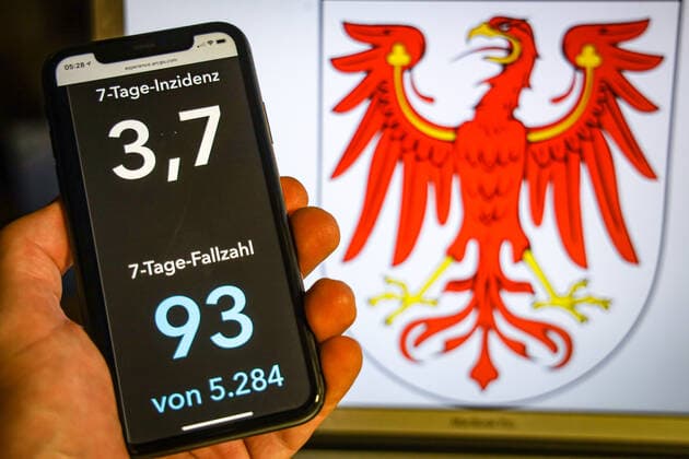 Coronavirus in Deutschland - Covid-19-Dashboard des Robert Koch-Institut DEU, Deutschland, Brandenburg, 12.07.2021: Die 7-Tage-Inzidenz für das Bundesland (Fälle letzte 7 Tage 100.000 EW) wird auf einem iPhone angezeigt, im Hintergrund das Landeswappen