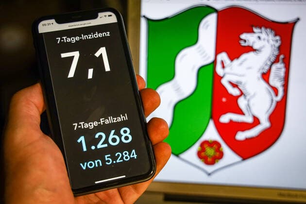 Coronavirus in Deutschland - Covid-19-Dashboard des Robert Koch-Institut DEU, Deutschland, Nordrhein-Westfalen, 12.07.2021: Die 7-Tage-Inzidenz für das Bundesland (Fälle letzte 7 Tage 100.000 EW) wird auf einem iPhone angezeigt, im Hintergrund das Landeswappen