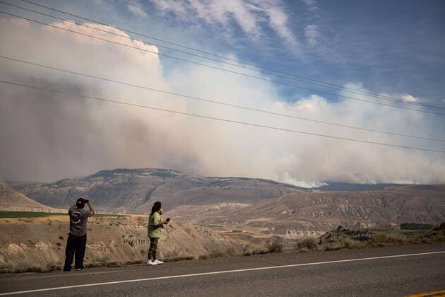 July 16, 2021, Ashcroft, BC, Canada: A man takes a photo and a woman eats an ice cream cone as they stop to view the Tremont Creek wildfire burning on the mountains above Ashcroft, B.C., on Friday, July 16, 2021. Ashcroft Canada  - ZUMAc35_ 20210716_zaf_c35_084 Copyright: xDarrylxDyckx