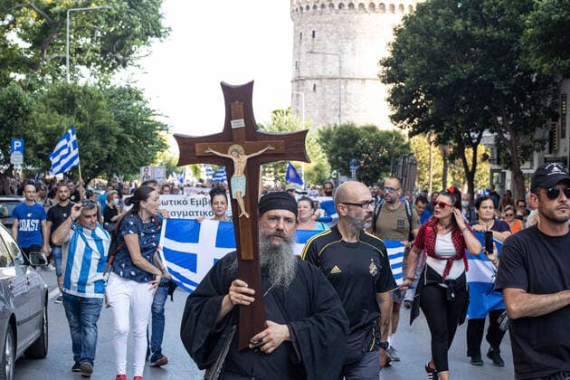 Demonstration Against The Mandatory Vaccine In Thessaloniki A priest holds a cross during a Demonstration Against The Mandatory Vaccine was held in Thessaloniki and Athens in Greece on Wednesday July 21, 2021. One week after the massive protest against the mandatory vaccination the anti-vaxx campaign continues with a big group protesting in the streets of the city of Thessaloniki. The protest was organized via social media by anti-vaccination believers. According to the group more than 40.000 people participated, while the police estimated unofficially slightly around 15.000 people participating in the demonstration. As the Greek government is passing a legislation with mandatory vaccination to specific job sectors like medical healthcare  Copyright: xNicolasxEconomoux