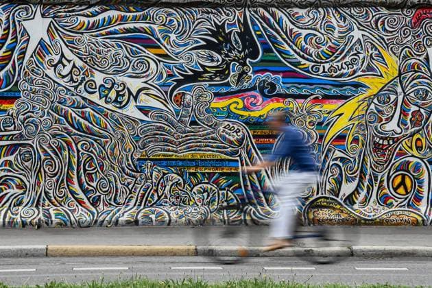 Berlin East Side Gallery 21 07 2021,A tourist rides a bike in Berlin at the East Side Gallery , the largest remaining piece of the Berlin Wall Copyright: xLakomski Eibner-Pressefotox EP_dli