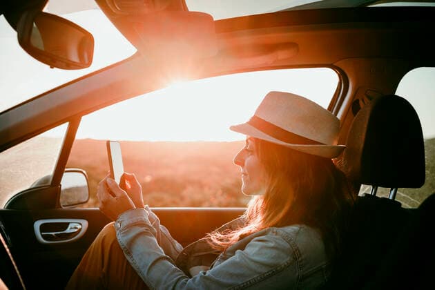 IMAGO Creative: Welttourismustag am 27. September Woman wearing hat using mobile phone while sitting in car model released Symbolfoto EBBF04063