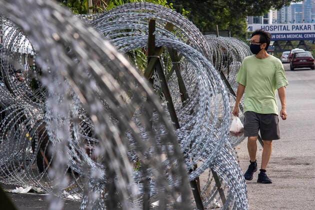 (210724) -- KUALA LUMPUR, July 24, 2021 -- A resident walks near the barbed wire in a community under the Enhanced Movement Control Order (EMCO) in Kuala Lumpur, Malaysia, July 24, 2021. Malaysia reported 15,902 new COVID-19 infections in the highest daily spike since the outbreak, bringing the national total to 996,393, the Health Ministry said Saturday. (Photo by Xinhua) MALAYSIA-COVID-19-CASES-NEW HIGH ChongxVoonxChung 