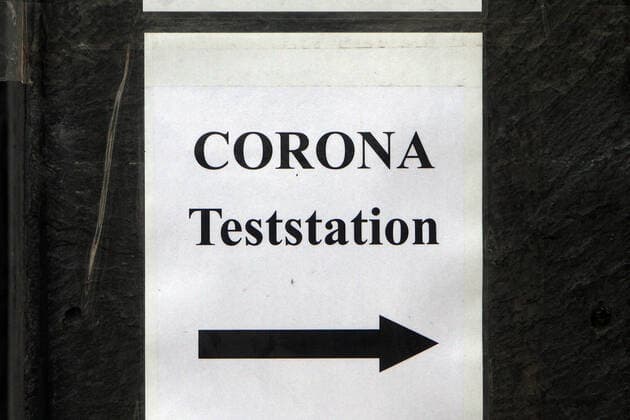 Note with inscription Corona Teststation with direction arrow stuck on a house wall in the city centre of Düsseldorf, North Rhine Westphalia, Germany