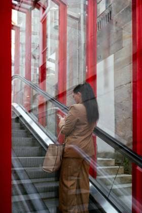 Business woman checking her cellphone on an escalator Vigo, Galicia, Spain CR_AIMA2107270E-802233-01 ,model released, Symbolfoto