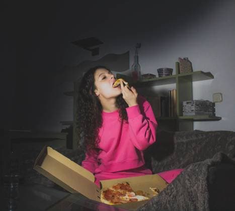 IMAGO Creative, Weihnachten, Tradition: Weihnachtsfilme sehen young woman eating pizza on the sofa watching a movie at night Madrid, MD, Spain CR_NELA210218A-648593-01 ,model released, Symbolfoto