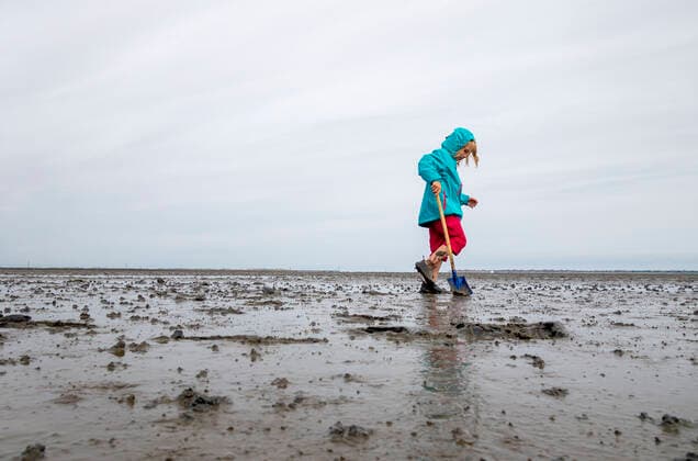 Girl playing in mud flat against sky at Lower Saxon Wadden Sea National Park, Germany model released Symbolfoto LHF00823