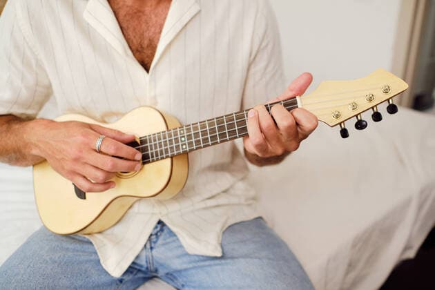Cropped unrecognizable male on white wall playing ukulele, Model released, Property released AntonioOvejero_WilliamSummer_17.jpg Copyright: xAntonioxOvejerox MR