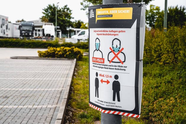 Gersthofen, Bavaria, Germany - 08 August 2021: Notes on compliance with FFP 2 mask requirement and compliance with minimum distance Covid 19 coronavirus protection measures in the parking lot of a German Aldi Süd grocery store