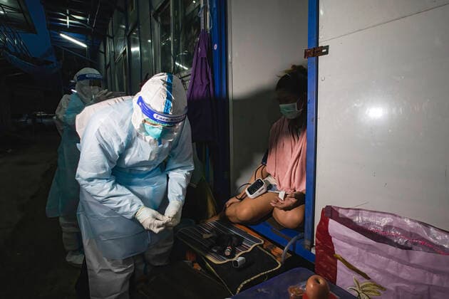 August 12, 2021, Bangkok, Thailand: A Zendai volunteer wearing a Personal Protective Equipment (PPE) suit checks pulse of a pregnant worker in construction workers camp at Laksi..Covid-19 check-up in construction workers camp in Bangkok. Bangkok Thailand - ZUMAs197 20210812_zaa_s197_052 Copyright: xVaruthxPongsapipattx
