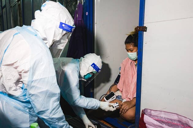 August 12, 2021, Bangkok, Thailand: A Zendai volunteer wearing a Personal Protective Equipment (PPE) suit checks pulse of a pregnant worker in construction workers camp at Laksi..Covid-19 check-up in construction workers camp in Bangkok. Bangkok Thailand - ZUMAs197 20210812_zaa_s197_054 Copyright: xVaruthxPongsapipattx