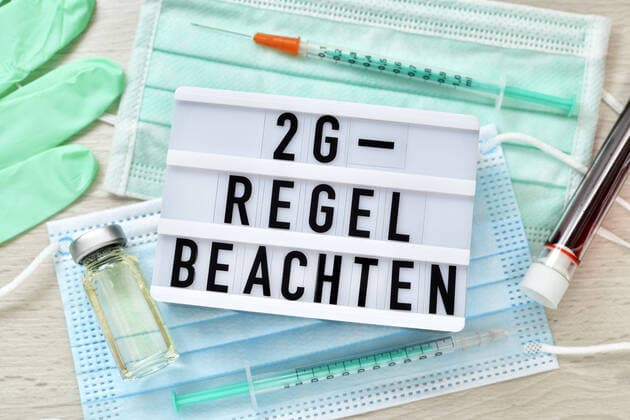 Sign with inscription 2G Rule observe on protective masks with vaccine and vaccination syringes ** NUR FUER REDAKTIONELLE ZWECKE ** EDITORIAL USE ONLY **