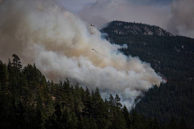 August 15, 2021, LYTTON, BC, CANADA: A helicopter carrying a water bucket flies past the Lytton Creek wildfire burning in the mountains near Lytton, B.C., on Sunday, August 15, 2021. LYTTON CANADA  - ZUMAc35_ 20210815_zaf_c35_093 Copyright: xDarrylxDyckx