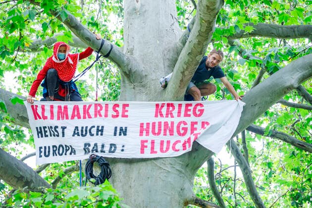 Bilder des Jahres 2021, News 08 August News Themen der Woche KW33 News Bilder des Tages Klima-Aktivisten besetzen Monbijou-Park Deutschland, Berlin am 16.08.2021: Zwei Klimaaktivisten mit Kletterseil hoch auf einem Baum. Sie zeigen ein Banner Klimakriese heisst auch in Europa bald: Krieg Hunger Flucht . *** Climate activists occupy Monbijou Park Germany, Berlin on 16 08 2021 Two climate activists with climbing rope high on a tree They display a banner Climate crisis means soon war hunger flight also in Europe