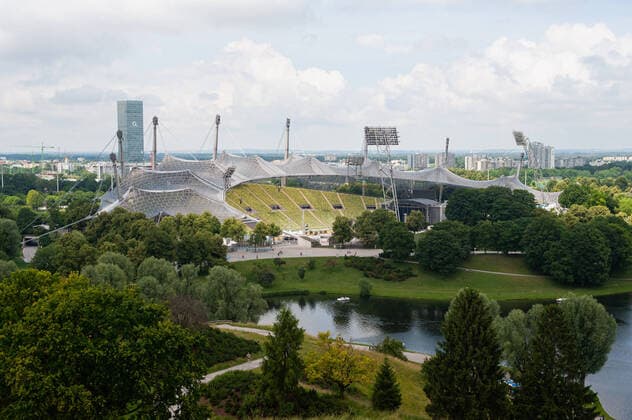 Architektur von Frei Otto 23.06.2019, Muenchen, Bayern, Deutschland, Europa - Blick vom Aussichtspunkt Olympiaberg auf das Muenchner Olympiastadion mit dem Olympiasee im Olympiapark und dem Hochhaus Uptown Muenchen im Hintergrund. *** 23 06 2019, Munich, Bavaria, Germany, Europe View from the vantage point Olympiaberg to the Munich Olympic Stadium with the Olympic Lake in the Olympic Park and the high-rise Uptown Munich in the background.