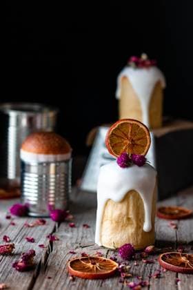 Several delicious homemade kulichs poured with sweet glaze and decorated with pieces of dry orange and flowers on wooden table PimientaDulce_VariousFood_70.jpg Copyright: xPimientaxDulcex Model Released