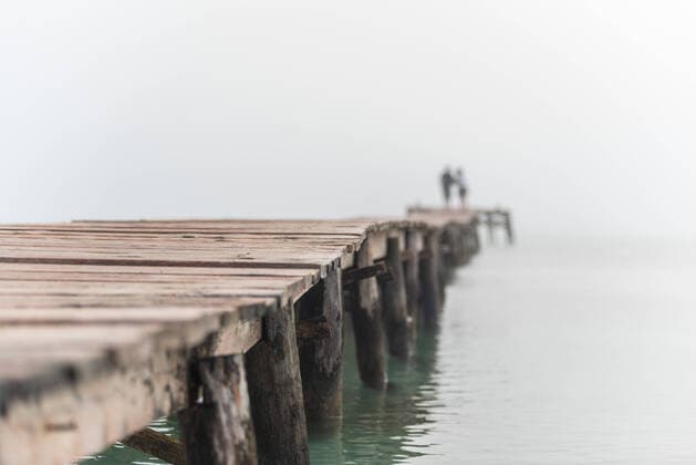 Creative Highlights Symbolbilder Unrecognizable blurred couple standing on wooden quay in sea water in foggy morning on Playa de Muro VictorPrieto_SummerMorning_7.jpg Copyright: xVictorxPrietox Model Released