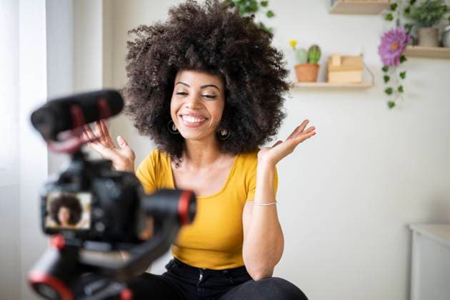 Happy young woman filming and vlogging through camera at home model released Symbolfoto property released JCCMF03136