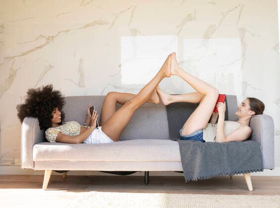 Young female friends lying on sofa at home model released Symbolfoto property released JCCMF03233