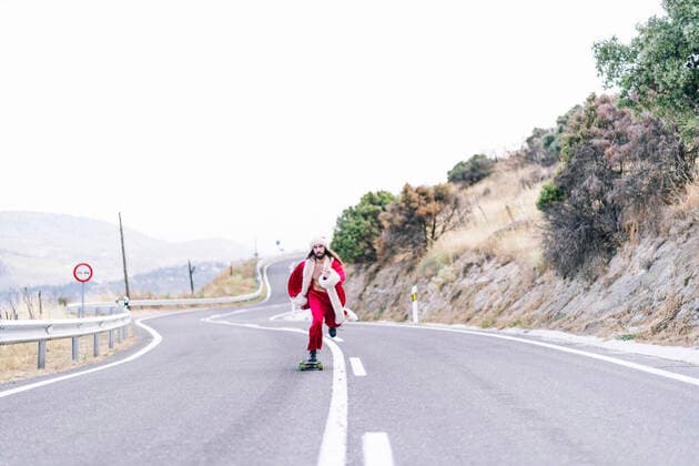 Young man in Santa Claus costume skateboarding on road model released Symbolfoto OCMF02197