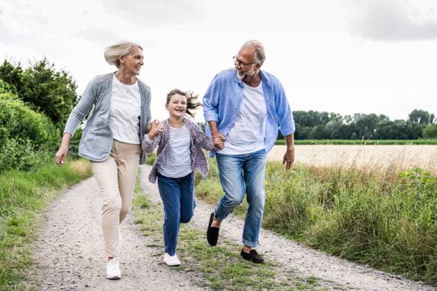 Cheerful grandparents playing with granddaughter while running on dirt road model released Symbolfoto UUF24175