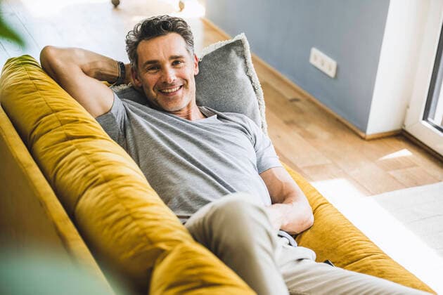 IMAGO Creative: Jahreszeit Winter, Couching Smiling man relaxing on sofa at home model released Symbolfoto property released UUF24574