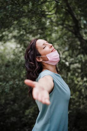 Mid adult woman standing with arm outstretched in forest during coronavirus outbreak model released Symbolfoto property released EBBF04479