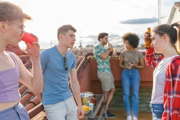 IMAGO Creative, Urban Lifestyle Multi-ethnic friends talking while having drinks on terrace during party model released Symbolfoto property released IFRF00994
