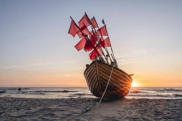 Lone fishing boat left on sandy shore at sunset KEBF02015