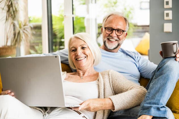 IMAGO Creative: Jahreszeit Winter, Couching Woman smiling at video call through laptop while sitting with man on sofa model released Symbolfoto property released UUF24074