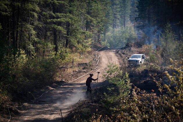 August 25, 2021, VERNON, BC, Canada: A wildland firefighter carrying an axe is silhouetted as he walks along a guard line while working on remaining hot spots from a controlled burn the B.C. Wildfire Service conducted to help contain the White Rock Lake wildfire on Okanagan Indian Band land, northwest of Vernon, B.C., on Wednesday, August 25, 2021. VERNON Canada  - ZUMAc35_ 20210825_zaf_c35_058 Copyright: xDarrylxDyckx