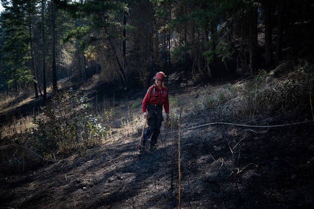 August 25, 2021, VERNON, BC, Canada: Wildland firefighter Katie Devaney carries an axe as she waits for a hose to be repaired while working to extinguish hot spots remaining from a controlled burn the B.C. Wildfire Service conducted to help contain the White Rock Lake wildfire on Okanagan Indian Band land, northwest of Vernon, B.C., on Wednesday, August 25, 2021. VERNON Canada  - ZUMAc35_ 20210825_zaf_c35_090 Copyright: xDarrylxDyckx