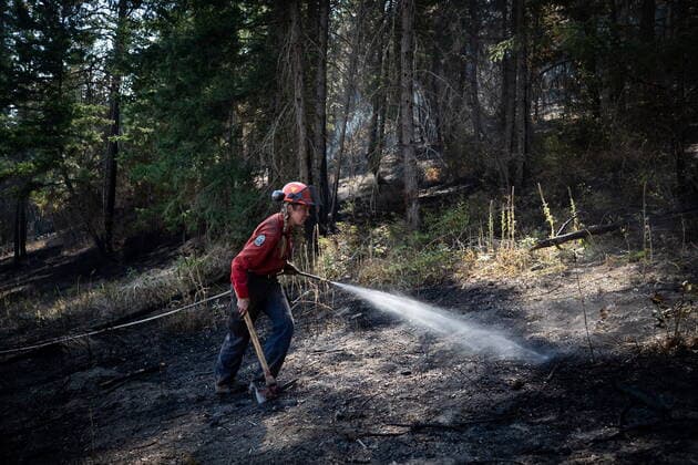 August 25, 2021, VERNON, BC, Canada: Wildland firefighter Katie Devaney carries an axe and hose as she works to extinguish hot spots remaining from a controlled burn the B.C. Wildfire Service conducted to help contain the White Rock Lake wildfire on Okanagan Indian Band land, northwest of Vernon, B.C., on Wednesday, August 25, 2021. VERNON Canada  - ZUMAc35_ 20210825_zaf_c35_091 Copyright: xDarrylxDyckx