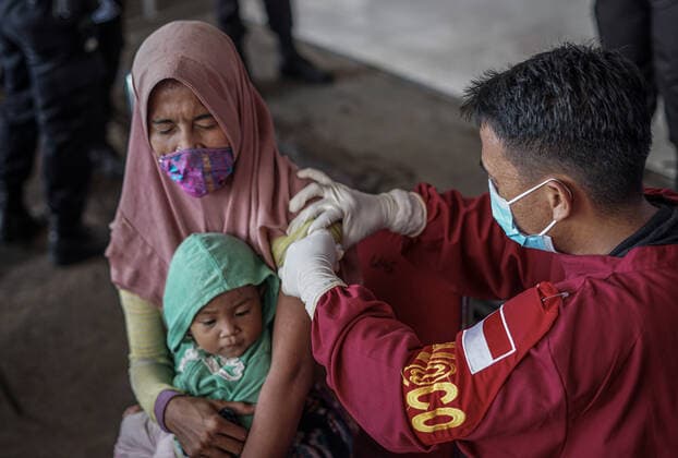 September 3, 2021, Makassar, South Sulawesi, Indonesia: A female beggar who is holding her child is being injected with the Covid-19 vaccine by health workers from the South Sulawesi Police Mobile Brigade. This free vaccination activity was carried out at the South Sulawesi Police Mobile Brigade Headquarters to meet the vaccine target for the people of South Sulawesi as much as 80 percent. Makassar Indonesia - ZUMAb223 20210903_zip_b223_002 Copyright: xHerwinxBaharx