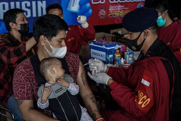 September 3, 2021, Makassar, South Sulawesi, Indonesia: A health worker who is also a member of the South Sulawesi Police Mobile Brigade injects the vaccine into a man who is holding his child. This free vaccination activity was carried out at the South Sulawesi Police Mobile Brigade Headquarters to meet the vaccine target for the people of South Sulawesi as much as 80 percent. Makassar Indonesia - ZUMAb223 20210903_zip_b223_008 Copyright: xHerwinxBaharx