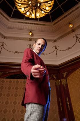 From below of classy adult male theater artist in burgundy jacket and with makeup pointing at camera and looking with question and arrogance MathiasAlvez_PerformanceInLocation_69.jpg Copyright: xMathiasxAlvezx Model Released