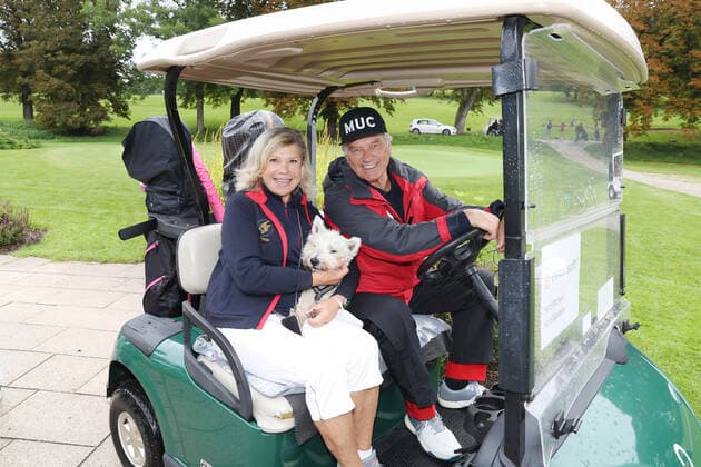 Tabaluga Golf Cup 2021 by Michael Roll For the 27th time Michael Roll organized the Tabaluga Golf Cup for the benefit of his Tabaluga Foundation Marianne and Michael Hartl together with their dog Winnie in a golf cart, Tutzing Bavaria Germany Golfclub Tutzing