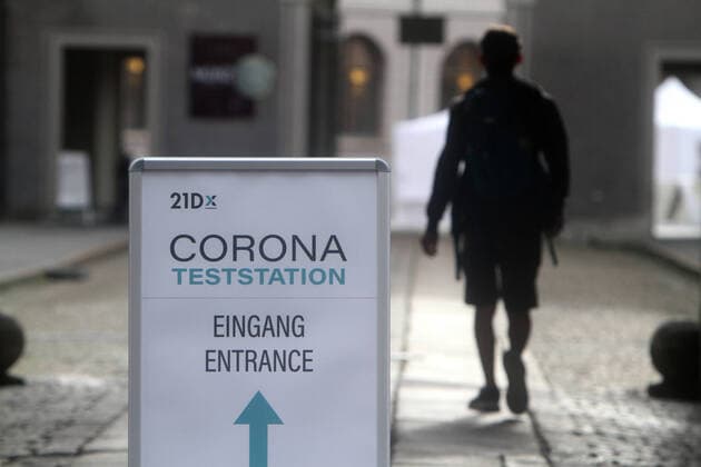 Stand with directional arrow and inscription 21D Corona test station stands in downtown Munich A man walks to the test, Bavaria, Germany
