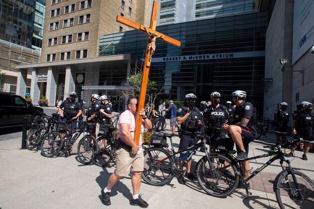 September 13, 2021, Toronto, Canada: A demonstrator walks past a line of police officers as protesters gather outside Toronto General Hospital, on Monday September 13, 2021, to protest against COVID-19 vaccines, COVID-19 vaccine passports and COVID-19 related restrictions. Toronto Canada  - ZUMAc35_ 20210913_zaf_c35_028 Copyright: xChrisxYoungx