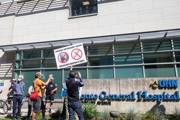 September 13, 2021, Toronto, Canada: A demonstrator gestures to watching healthcare workers as people gather outside Toronto General Hospital, on Monday September 13, 2021, to protest against COVID-19 vaccines, COVID-19 vaccine passports and COVID-19 related restrictions. Toronto Canada  - ZUMAc35_ 20210913_zaf_c35_029 Copyright: xChrisxYoungx