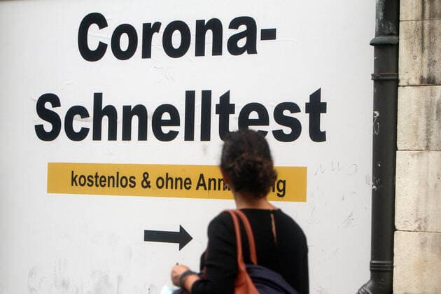 Writing Corona Schnelltest kostenlos und ohne Anmeldung mit Richtungspfeil emblazoned on a taped-up shop window in downtown Munich, Bavaria, Germany