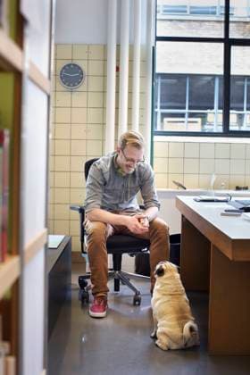 IMAGO Creative, Health, Hunde im Büro reduzieren Stress Young man looking down at cute dog from office desk, 06.02.2015, Copyright: xFrankxVanxDelftx, model released, wearing,looking down,working,animal,domestic dog,pug,one animal,copy space,small business,city living,aspiration,cute,loyalty,obedience,distraction,ambition,happiness,desk,20 to 24 years,caucasian ethnicity,male,man,only one young man,one person,businessman,office worker,indoors,office interior,day,business,casual clothing,eyeglasses,sitting,smiling,companion,dog,work,only male,animal themes,casual business,February 2015 Release,Sitting,Looking Down,Working,Caucasian Ethnicity,Young Adult,20-24 Years,Male,Men,Businesspeople,Office Worker,Businessman,Aspiration,City Life,Cute,Loyalty,Obedience,Wellbeing,Happiness,One Animal,One P Ref:IS09AP1EY