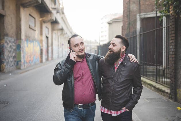 IMAGO Creative: Urban Diversity Gay couple walking on street, 02.07.2015, Copyright: xEugenioxMarongiux, model released, wearing,telephone call,holding,walking,black hair,burgundy red,diminishing perspective,focus on foreground,half length,city living,real people,bonding,carefree,freedom,harmony,quality time,togetherness,affection,confidence,friendship,happiness,love,relaxation,25 to 29 years,caucasian ethnicity,male,man,young man,couple,homosexual couple,young couple,two people,beard,mustache,wall,city,outdoors,day,street,leather jacket,shirt,communication,arm around,hand in pocket,smiling,standing,technology,graffiti,leisure,networking,relationship,enjoyment,only male,smartphone,hand over shoulder,July 2015 Release,buildings,Walking,On The Phone,Hands In Pockets,Stan Ref:IS09AS2T0