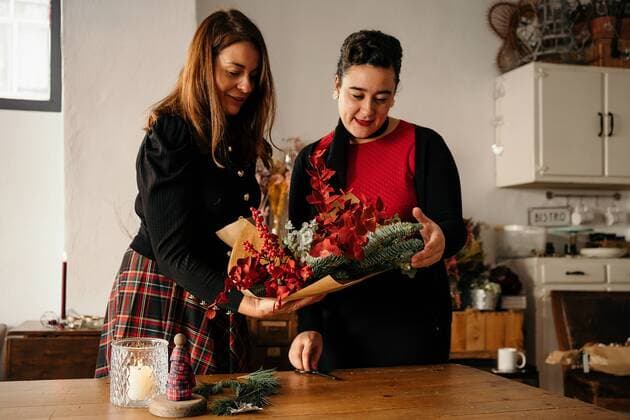Diversity, Weihnachten Cheerful female friends standing at table with candles and making creative Christmas bouquets for holiday celebration, Model released GustavoPozo_ChristmasDecoration_34.jpg Copyright: xGustavoxPozox MR