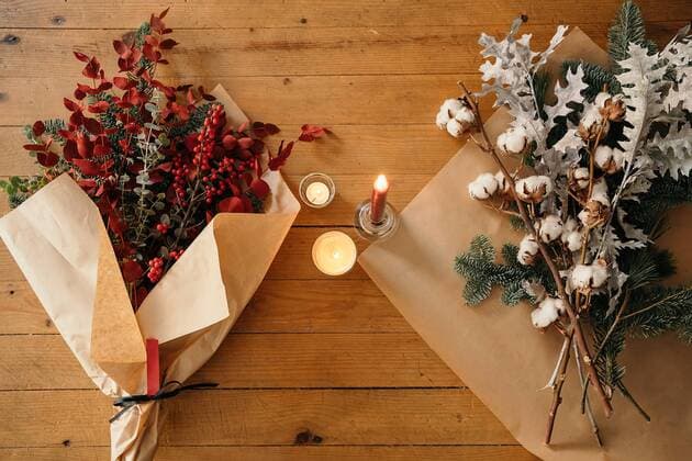 From above of festive Christmas bouquet with branches of cotton, fir and twigs of eucalyptus and bright red branches with berries placed on wooden table with candles in room, Property released GustavoPozo_ChristmasDecoration_9.jpg Copyright: xGustavoxPozox Model Released