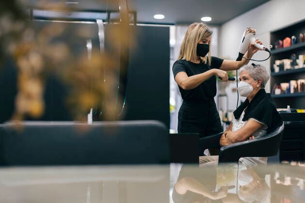 Female hairdresser with face mask blow drying customer s hair in salon model released Symbolfoto property released OCAF00767