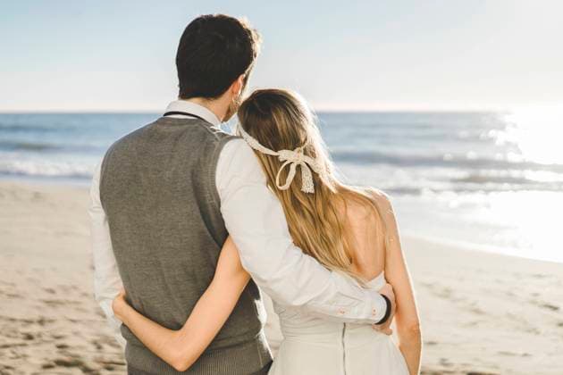 Newlywed couple with arm around standing on beach model released Symbolfoto AFVF09158