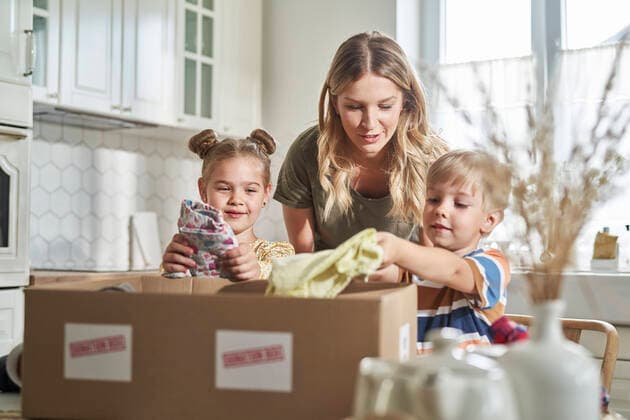 IMAGO Nature: Unsere Erde, Umweltverträgliche Herausforderungen, Recycling Woman talking with children packing clothes in donation box at home model released Symbolfoto property released ABIF01564