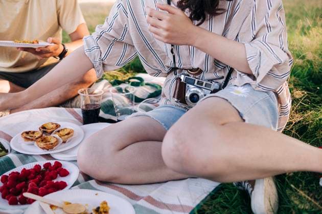IMAGO Creative: Jahreszeit Frühling, Picknick Friends having food while sitting on picnic blanket model released Symbolfoto ASGF01400